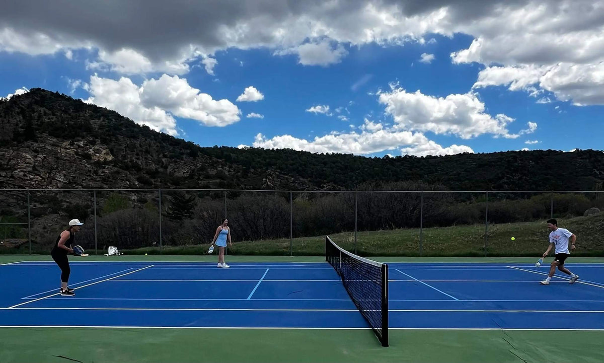 Pickleball court with blue and green playing surfaces, white boundary lines and central net, illustrating How to Keep Score in Pickleball.
