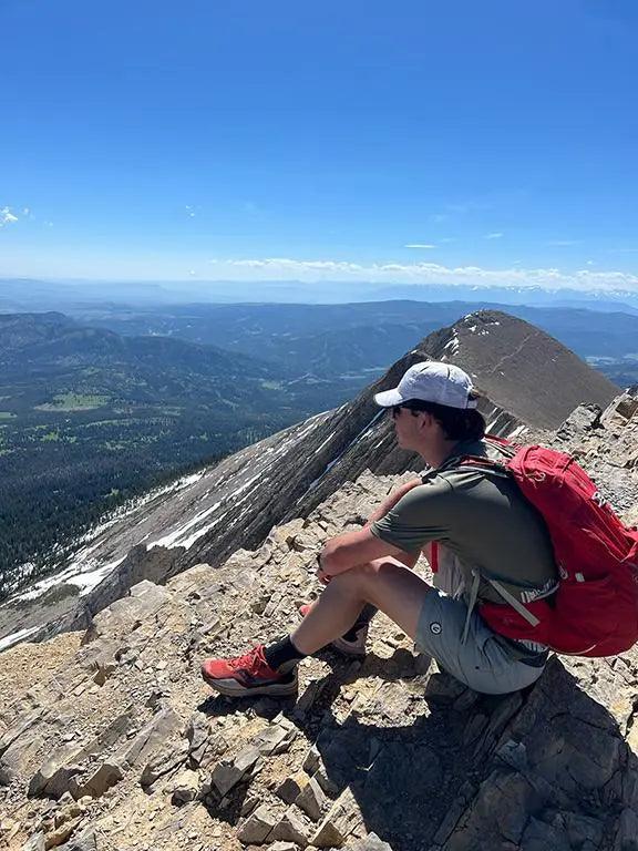 Footwear: red trail shoes with black accents and sturdy soles, worn for hiking on rugged rocky terrain