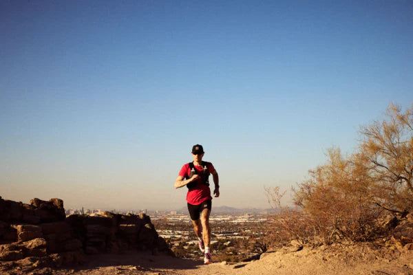 SaySky running apparel shown on a runner in a red short-sleeve shirt, black shorts, and a black cap