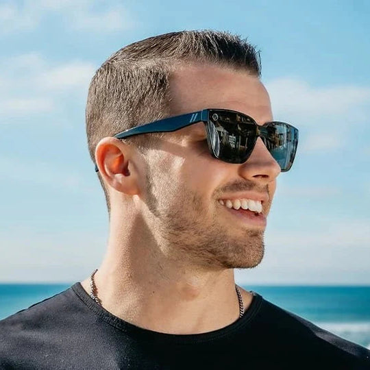 Man wearing sunglasses with a beach and blue sky in the background