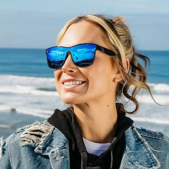 Woman wearing sunglasses with a beach and ocean in the background