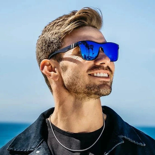 Man wearing blue sunglasses with a clear blue sky and ocean background