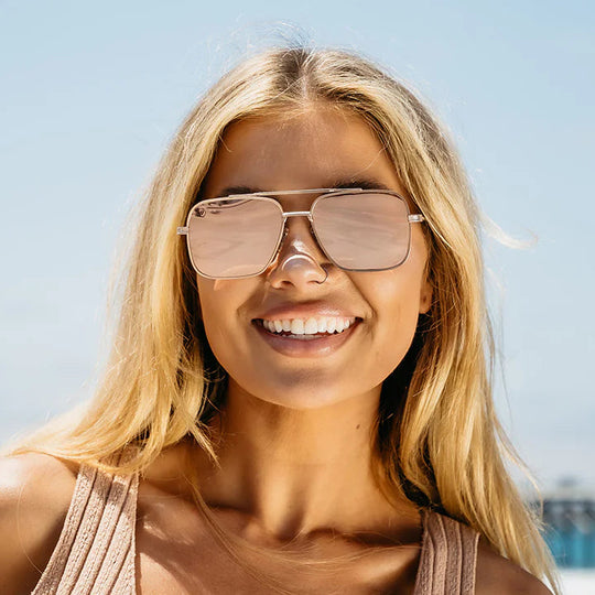 Woman wearing sunglasses with a clear blue sky and water background