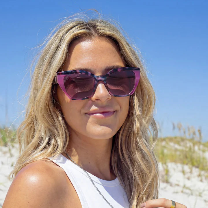 Woman wearing sunglasses on a beach with clear blue sky