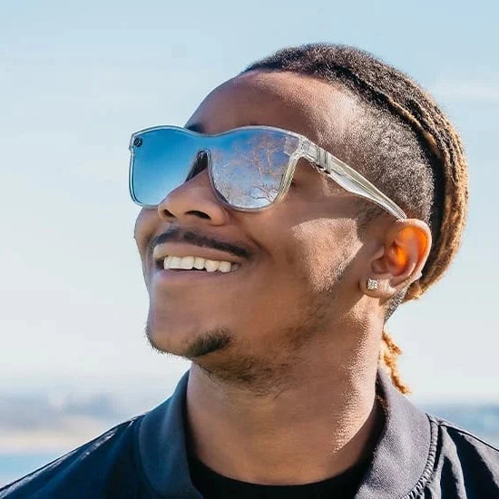 Man wearing reflective sunglasses with a clear blue sky background