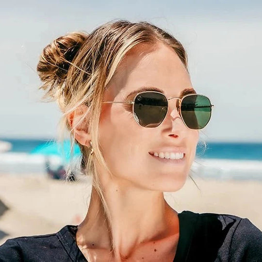 Woman wearing sunglasses on a beach with a blurred background