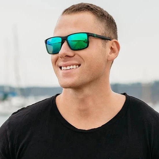 Man wearing green reflective sunglasses with a marina background