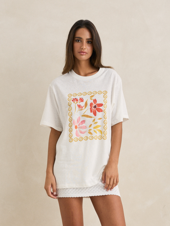 Woman wearing a white t-shirt with floral designs on a beige background