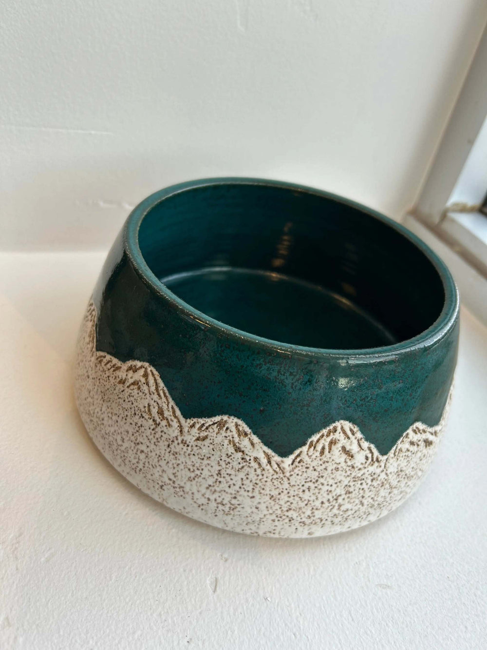 Wondrous Waters Pet Bowl, handmade ceramic in deep teal with a cream speckled mountain pattern around the base.
